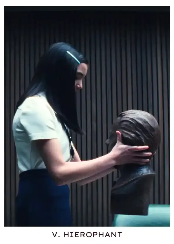 Hierophant: Huang holds up Jame Eagan's bust during a ritual that will allow her to participate in the Wintertide Fellowship, in which she must break a precious possession (in this case, her only toy) to show maturity, as is tradition.